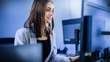 Happy smiling woman in modern office reading e-mails